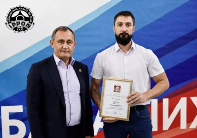 Вручение благодарственного письма тренеру клуба «ИППОН»; на фотографии двое мужчин, один держит письмо в рамке.